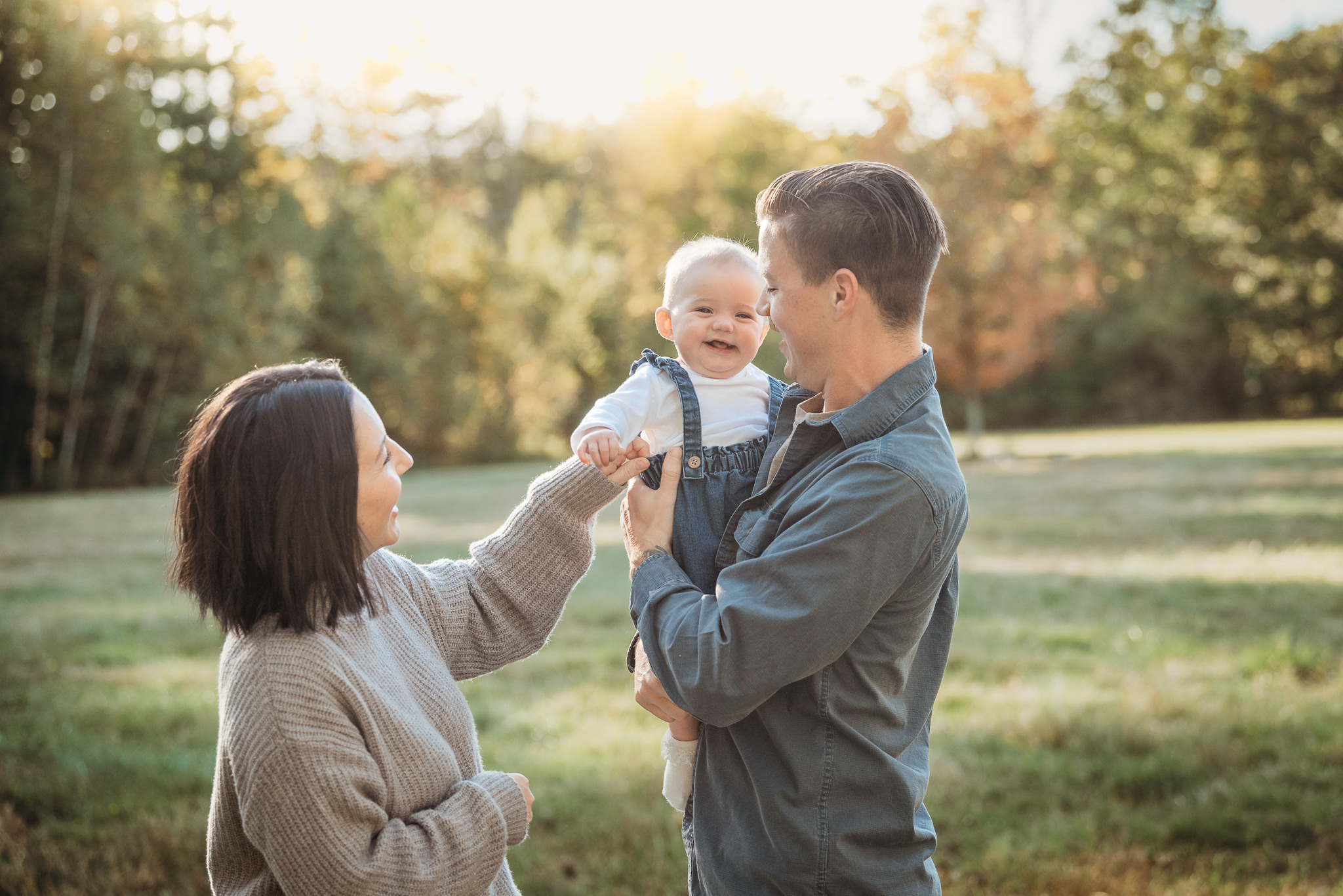 A young family playing with their young child during a milestone portrait photography session
