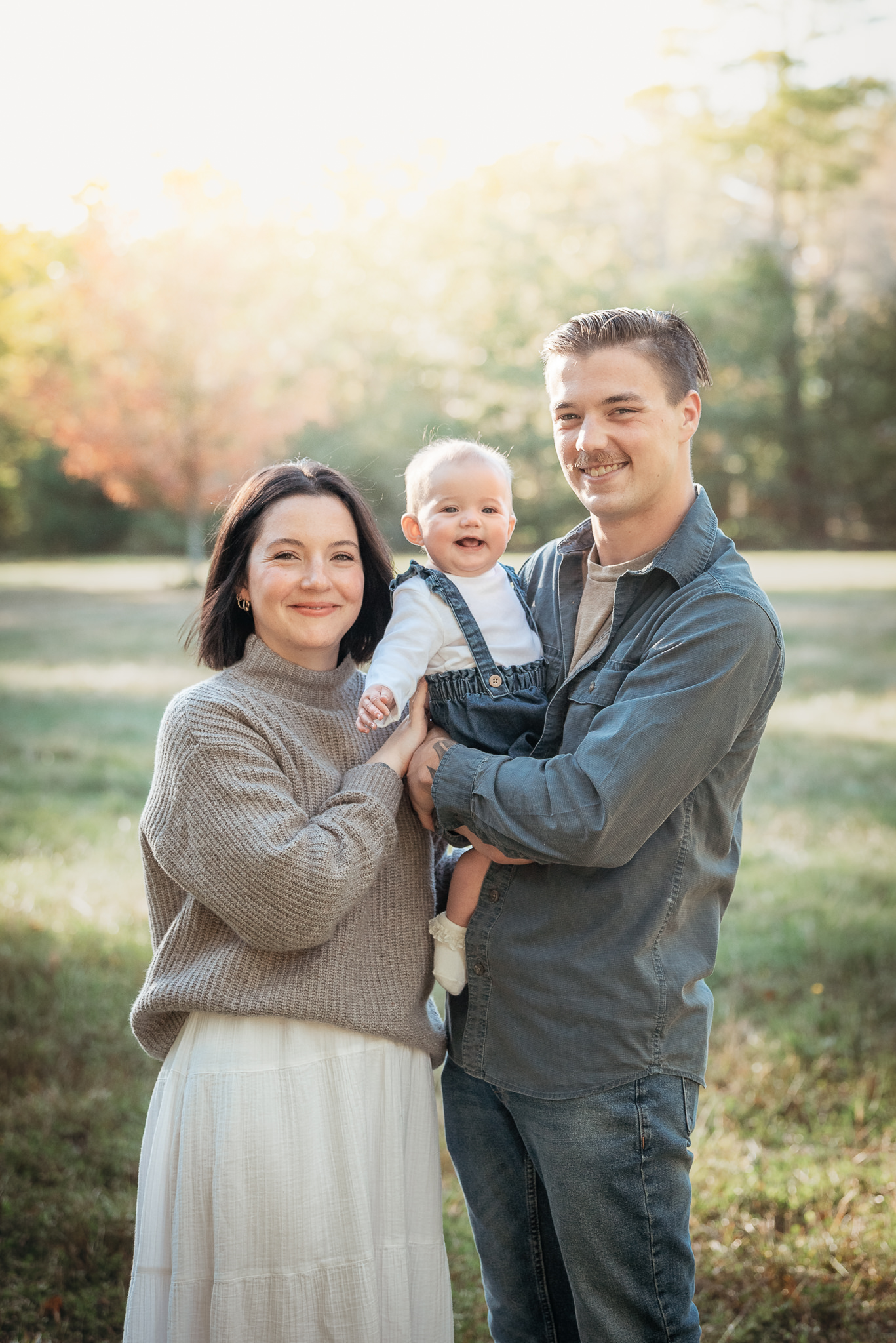 A young family smiling with their young child during a milestone portrait photography session